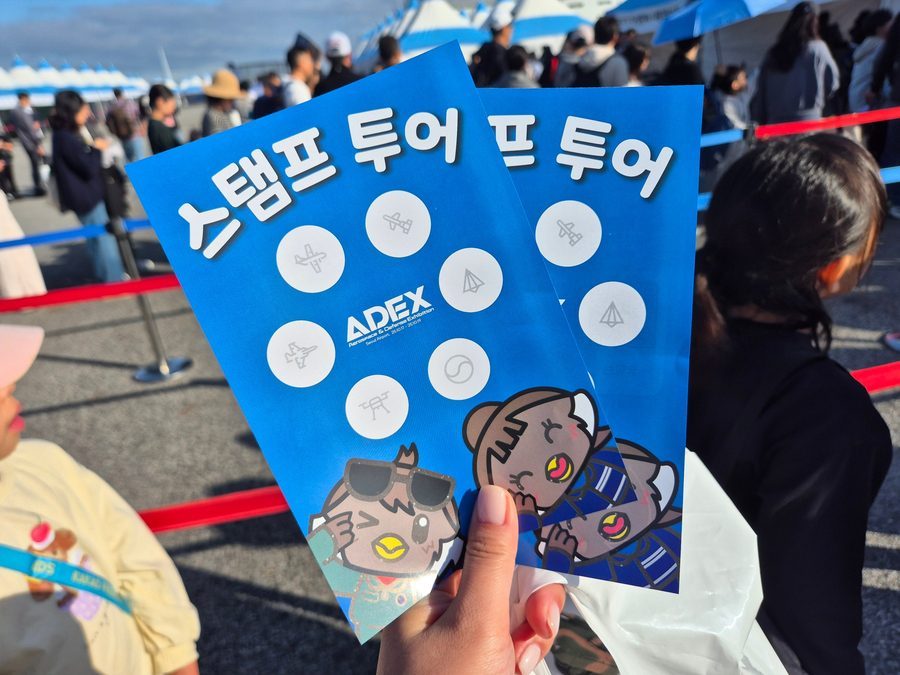 Visitors holding stamp tour cards on the flight line