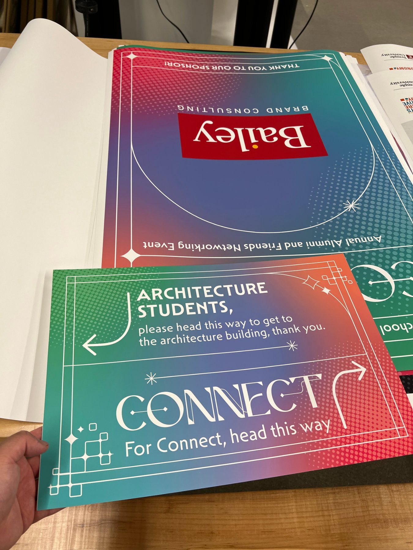 Freshly printed courtyard wayfinding and sponsor panels on the studio bench